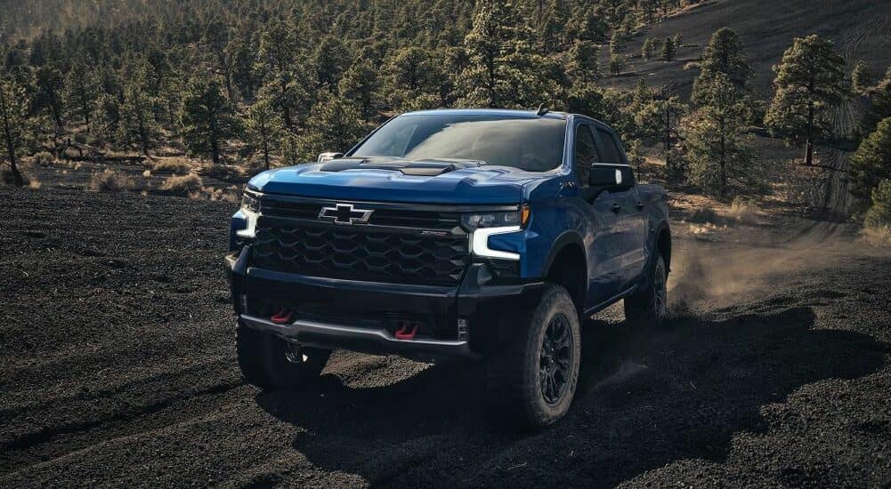 A blue 2024 Chevy Silverado 1500 ZR2 is shown driving off-road after visiting a used Chevy dealer.