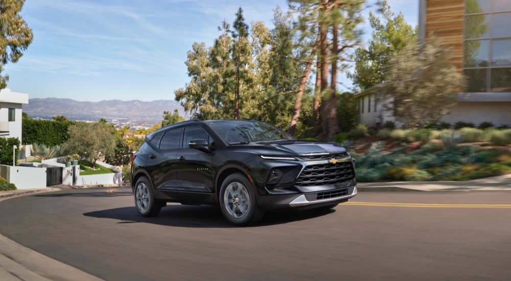 A black 2024 Chevy Blazer is shown driving in a suburb.