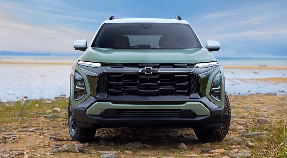 A green 2025 Chevy Equinox is shown from a front angle while parked off-road.