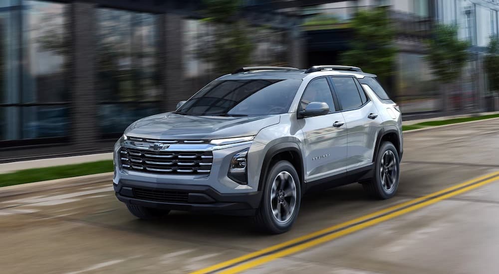 A silver 2025 Chevy Equinox is shown driving in a city.