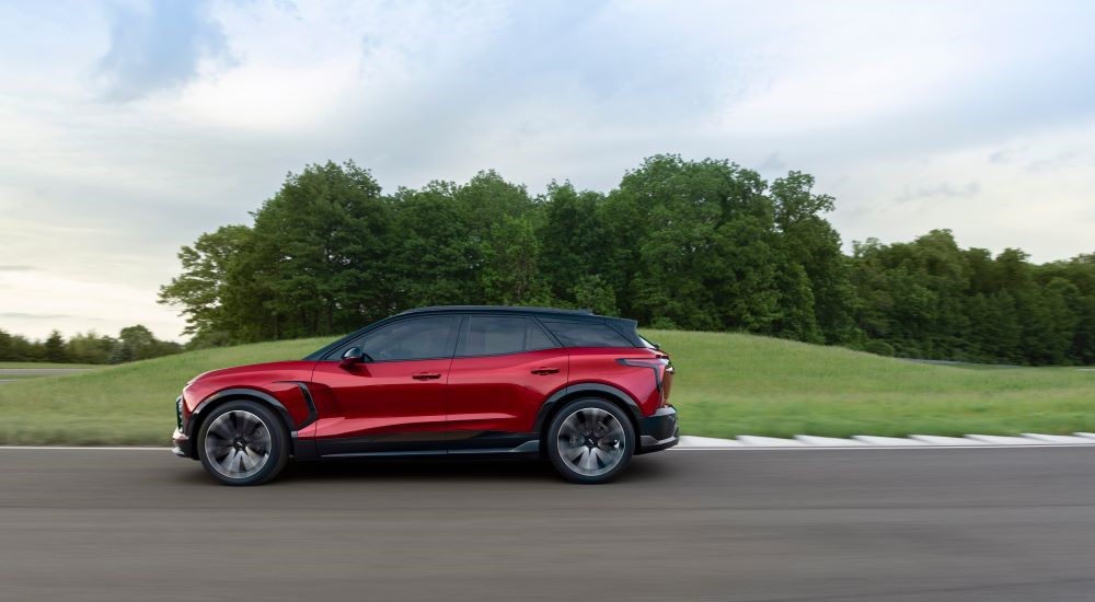 Side angle view of a red 2024 Chevy Blazer EV SS driving around a track.