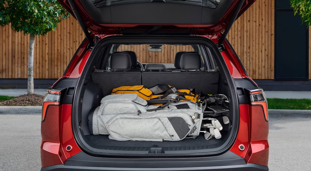 Rear view of a red 2025 Chevy Equinox with an open hatchback and golf cubs stored in the back.