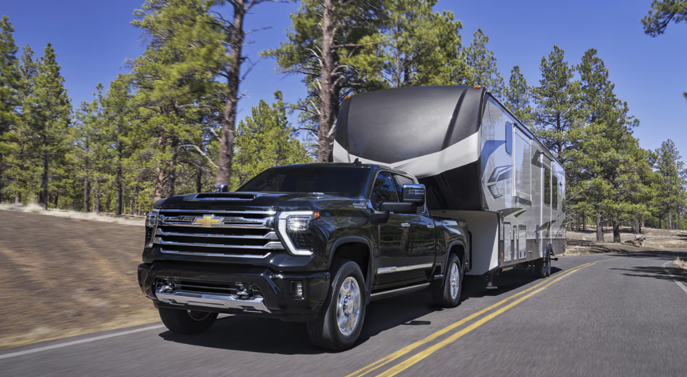 Black 2026 Chevy Silverado 3500 HD towing a camper.