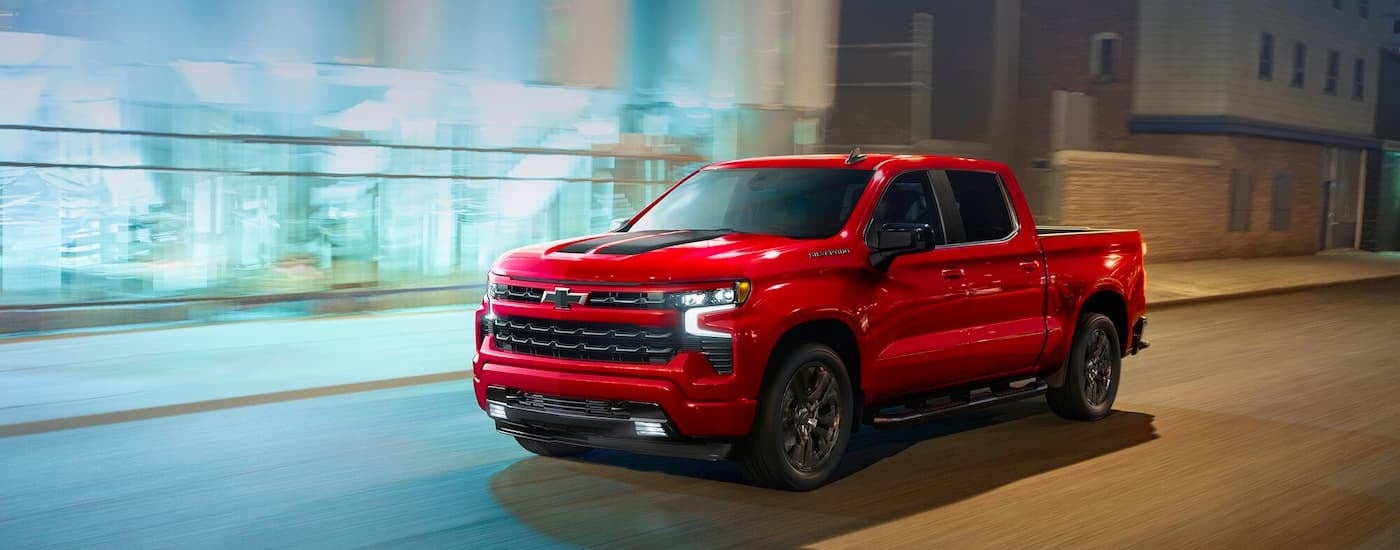 Red 2023 Chevy Silverado 1500 RST driving down a city street.