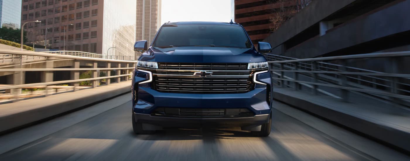Front of a dark blue 2023 Chevy Tahoe driving across a bridge.