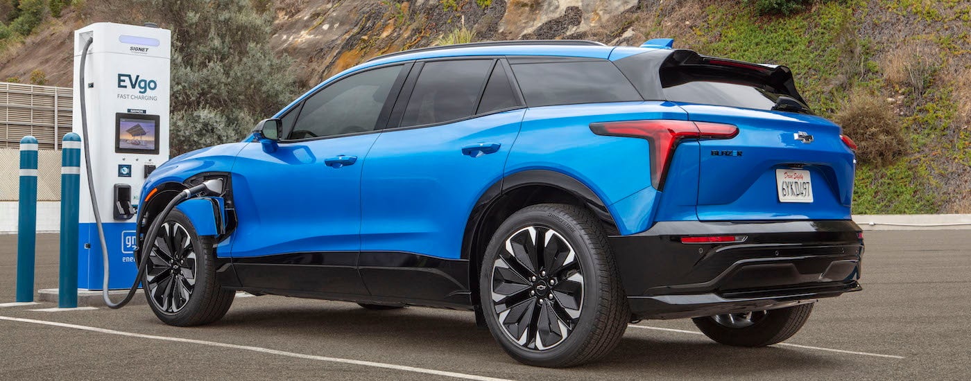 A blue 2024 Chevy Blazer EV RS is shown from the side while charging.