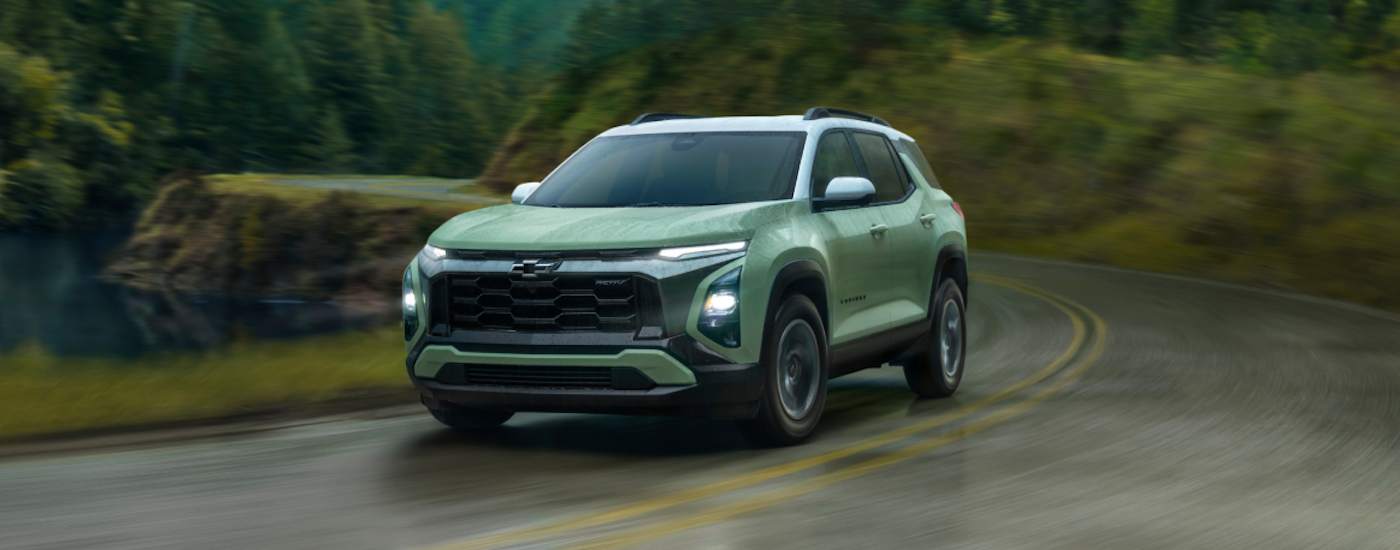 A green 2025 Chevy Equinox ACTIV driving around a bend from a dealer with a Chevy Equinox for sale near South Lyon.