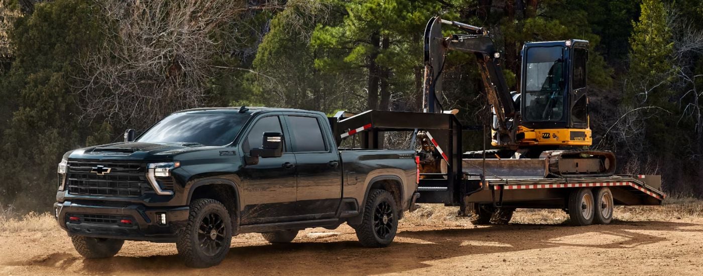 Green 2026 Chevy Silverado 2500 HD Trail Boss towing an excavator.
