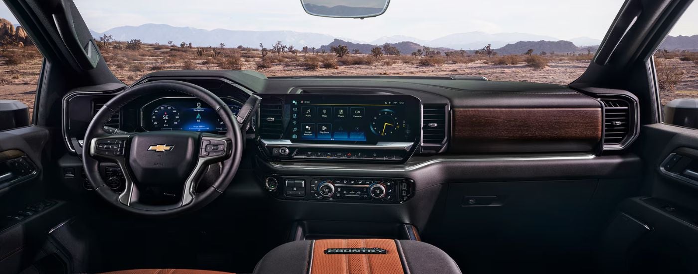The front interior of a 2026 Chevy Silverado 2500 HD showing the infotainment display and steering wheel.