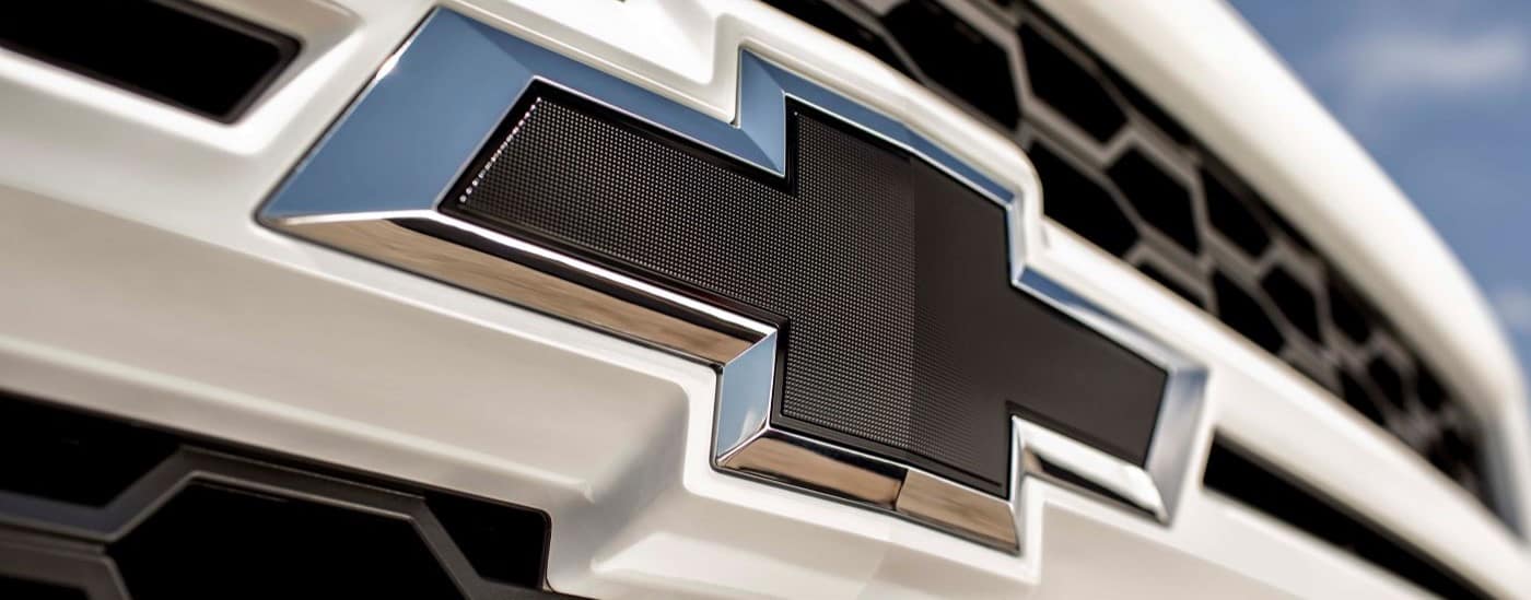 A close up shows the Chevy badge on a white 2015 Chevy Silverado 1500 Rally Edition.