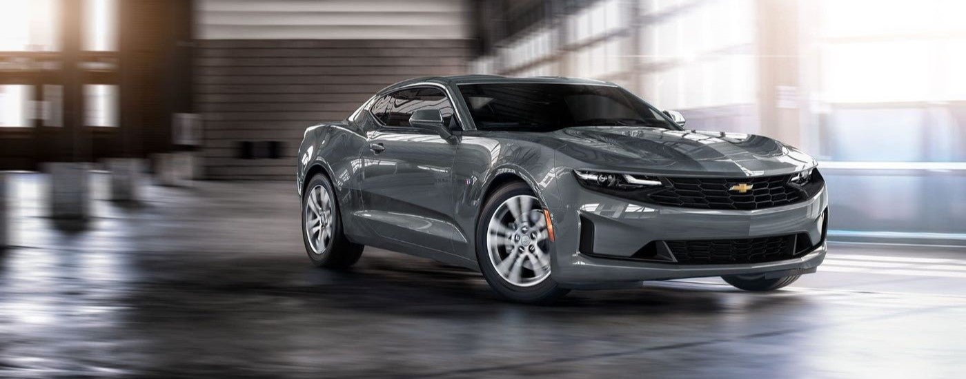 A grey 2024 Chevy Camaro is shown against a blurred background.