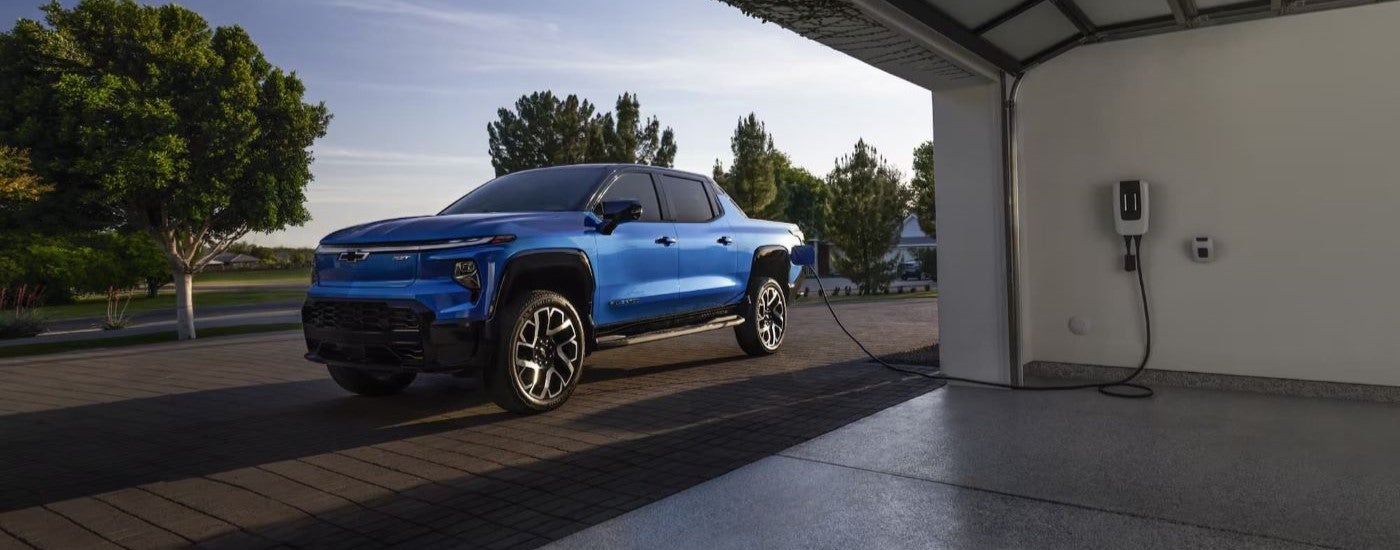 A blue 2024 Chevy Silverado EV RST is shown charging after leaving a Chevy dealer near Brighton.