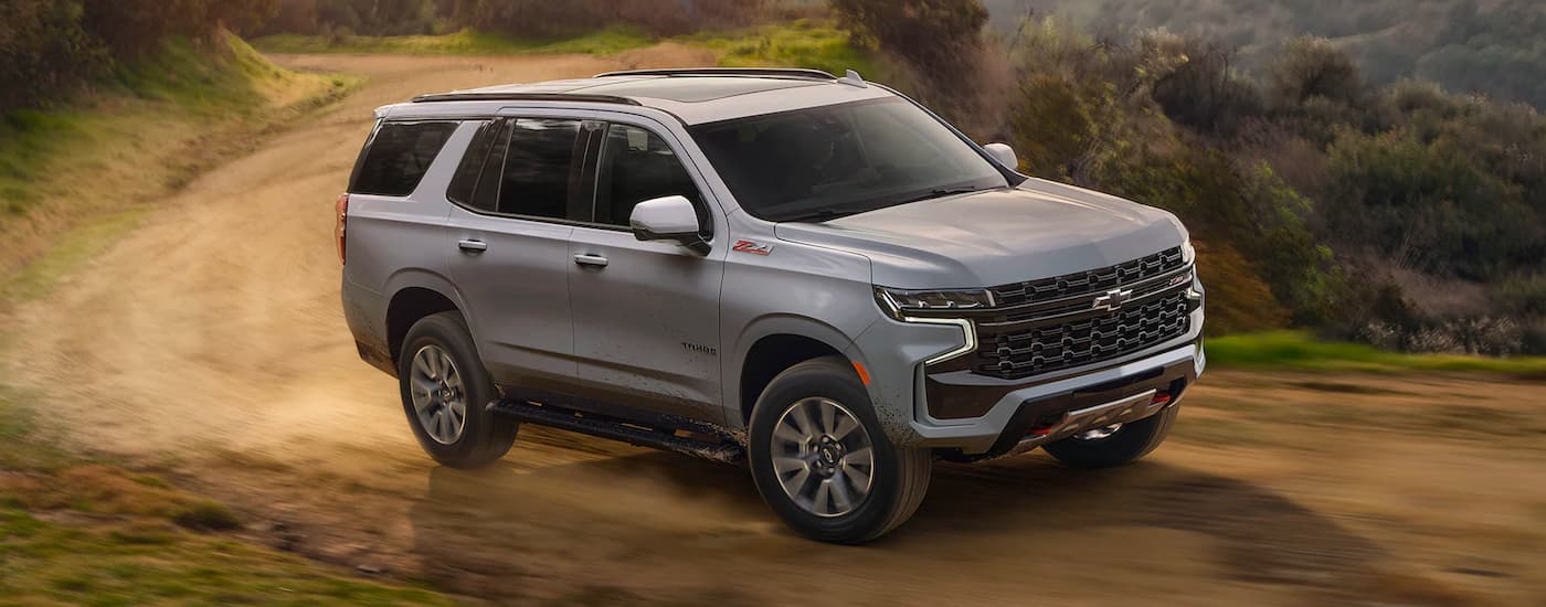 A grey 2024 Chevy Tahoe Z71 driving around a dirt bend from a Chevy dealer near Jackson.