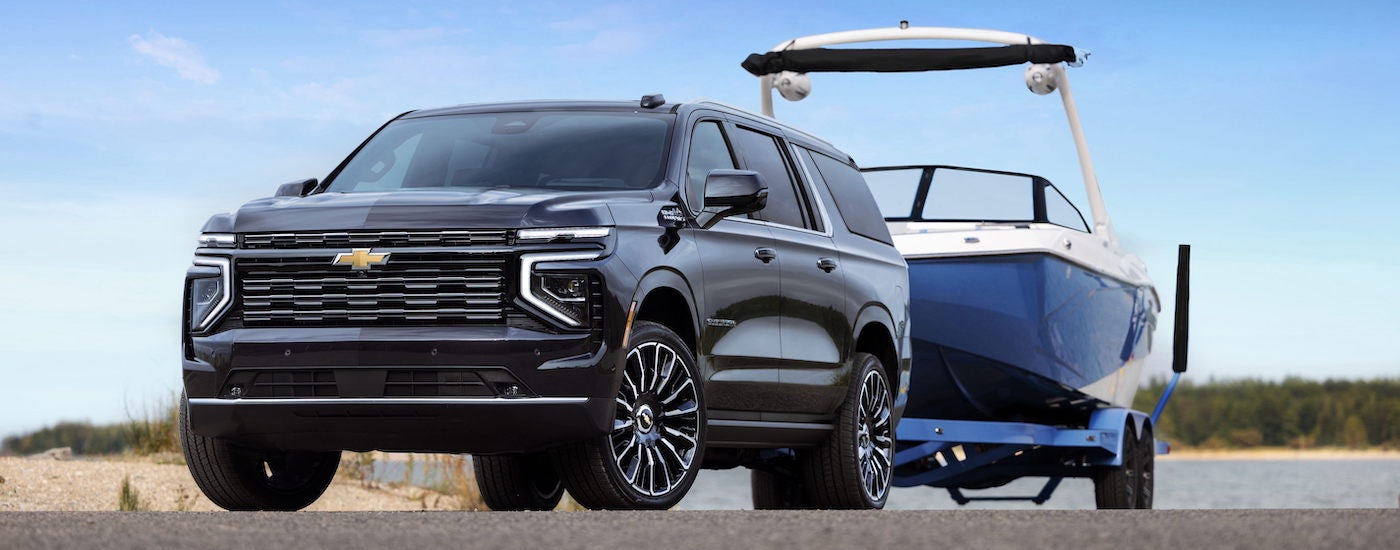 A black 2025 Chevy Suburban High Country towing a boat.