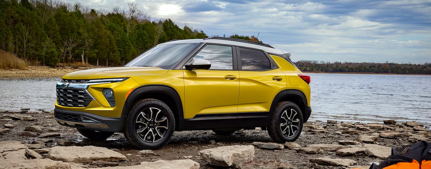 A yellow 2025 Chevy Trailblazer ACTIV parked on a lake shore and angled left.
