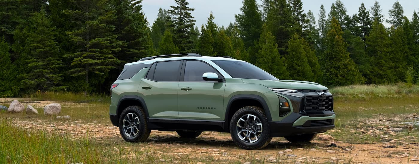 Side angle view of a green 2025 Chevy Equinox ACTIV parked off-road on a field.