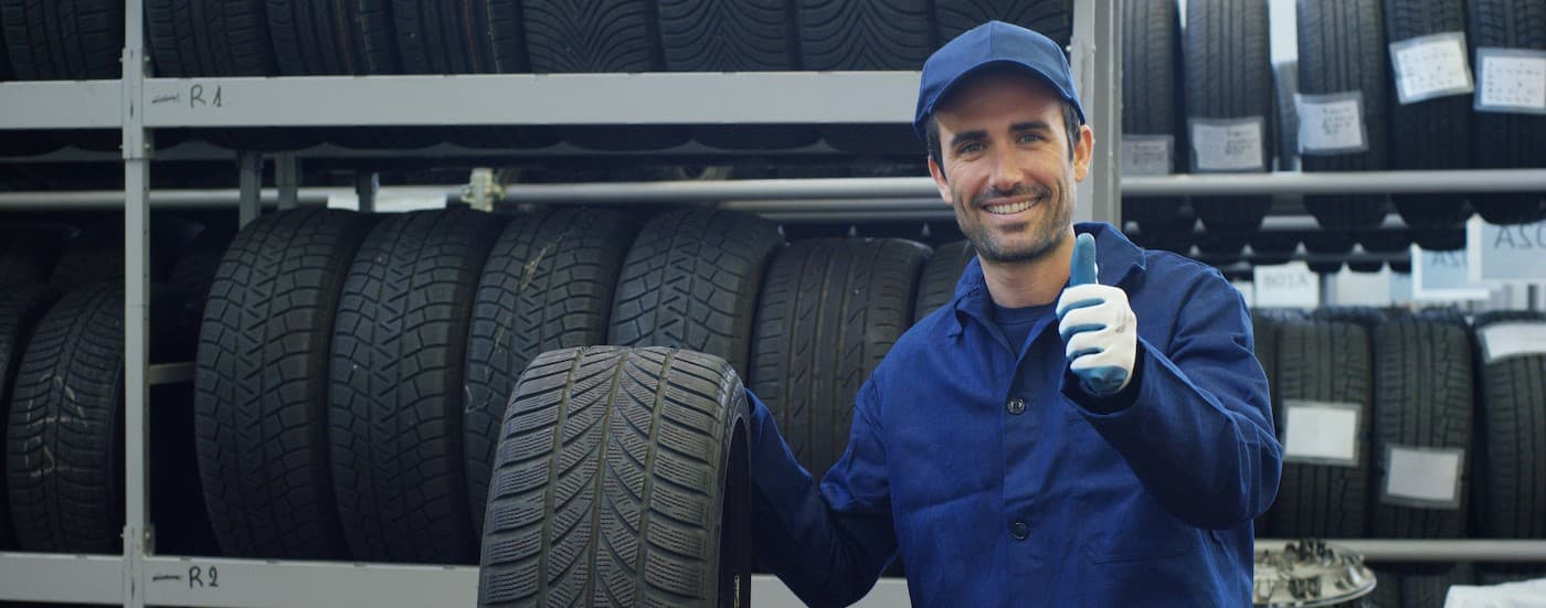 A technician giving a thumbs up at a tire shop.